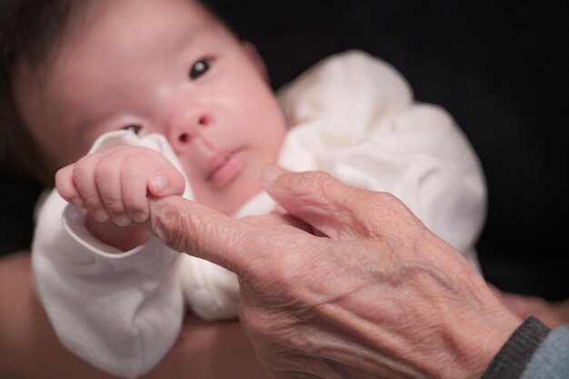 Baby hält die Hand einer älteren Frau