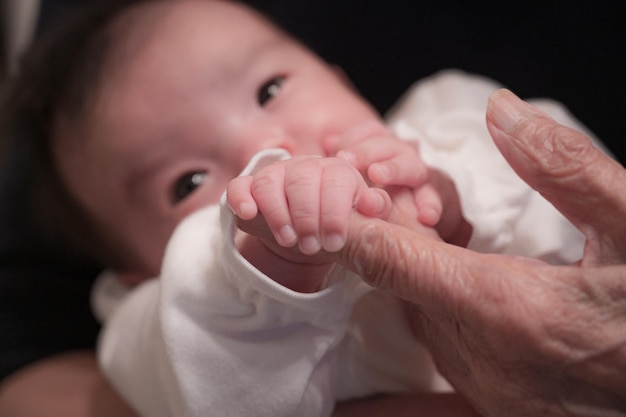 Baby hält die Hand einer älteren Frau