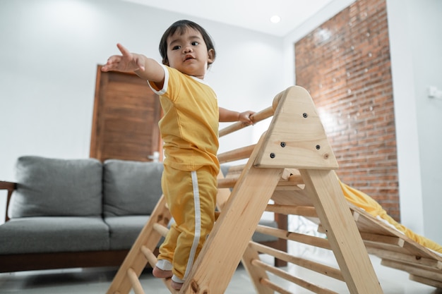 Baby hat Angst, beim Klettern auf dem Pikler-Dreieck im Wohnzimmer nach Hilfe zu greifen