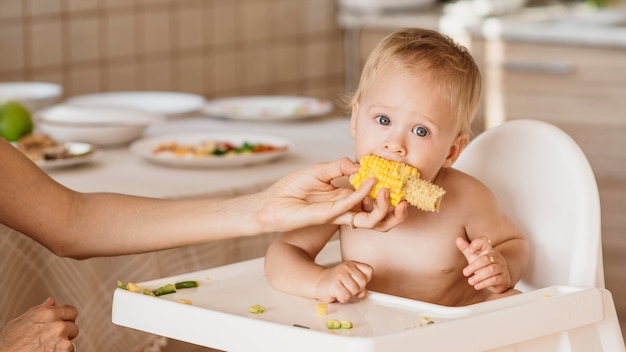 Foto baby im hochstuhl, der mais isst