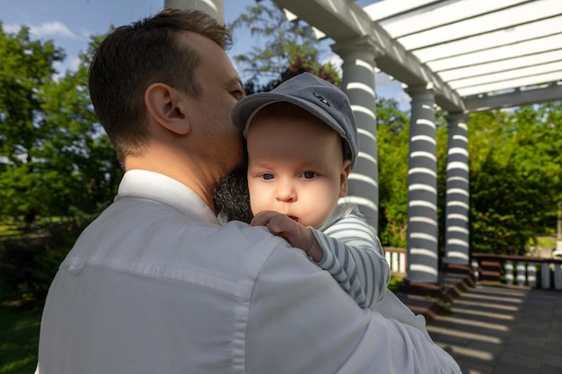 Baby in den Armen von Papa an einem sonnigen Tag auf hellem Hintergrund