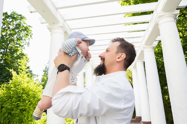 Baby in den Armen von Papa an einem sonnigen Tag auf hellem Hintergrund