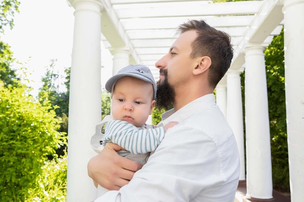 Baby in den Armen von Papa an einem sonnigen Tag auf hellem Hintergrund