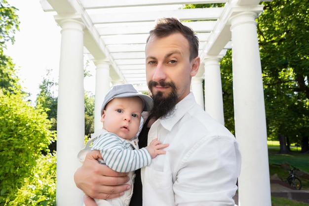 Baby in den Armen von Papa an einem sonnigen Tag auf hellem Hintergrund