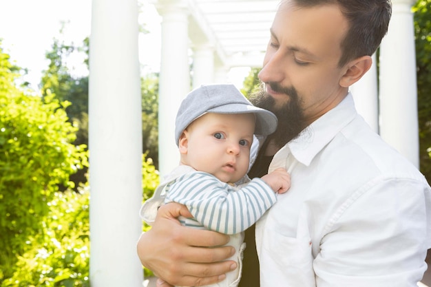 Baby in den Armen von Papa an einem sonnigen Tag auf hellem Hintergrund