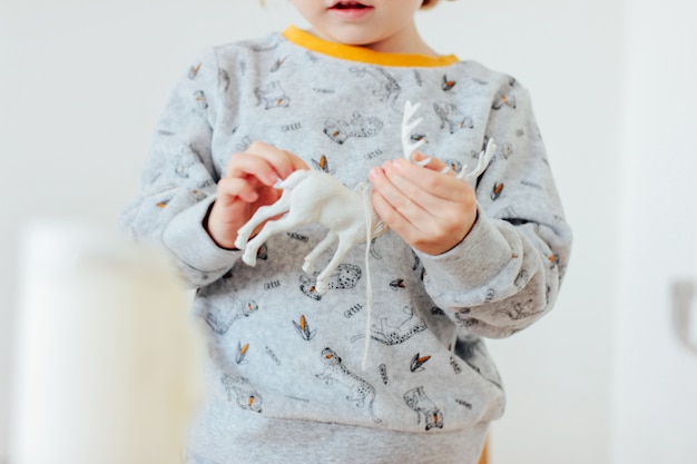 Baby in den Pyjamas, die ein Weihnachtsspielzeugrotwild, Abschluss hochhalten