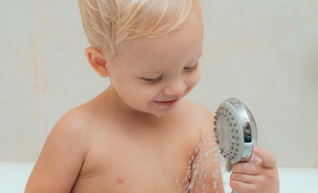 Baby in der Badewanne Porträt eines lächelnden Kindes glückliches lachendes Baby, das ein Bad nimmt und mit Schaumblasen spielt