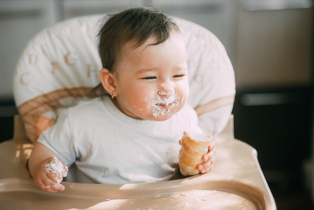 Baby in der Küche eifrig die leckeren Sahnehörner essen, gefüllt mit einer Vanillecreme sehr lustig