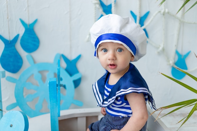 Baby in der Seezone mit einem Schiff in einer Seemannsweste, das Konzept der Sommerferien