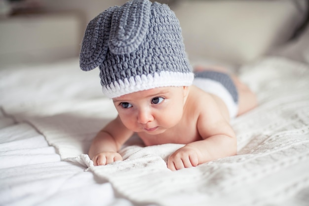 Baby in einem gestrickten Hasenanzug liegt auf dem Bauch