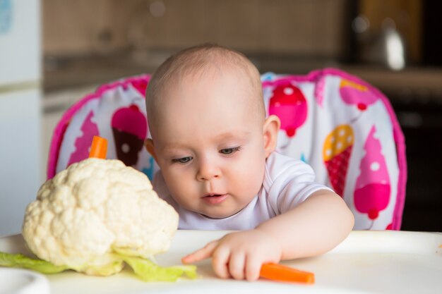 Baby in einem Kindersitz Gemüse essen