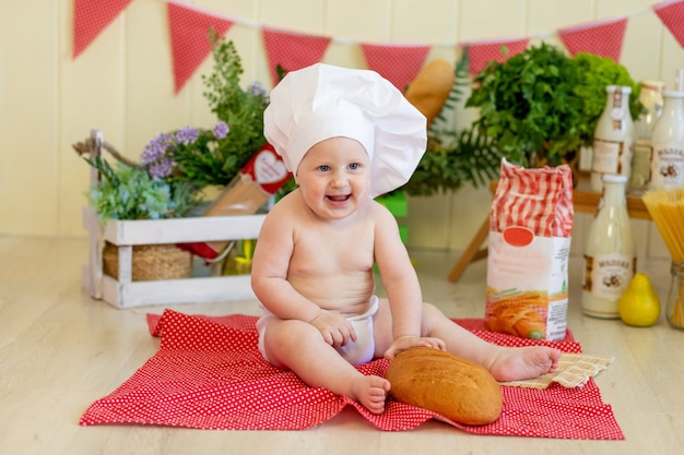 Baby in einem Kochhut mit Essen um ihn herum