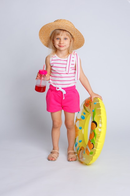 Baby in Sommerkleidung und Schwimmkreis mit Saft in ihren Händen. Das Konzept der Sommerferien