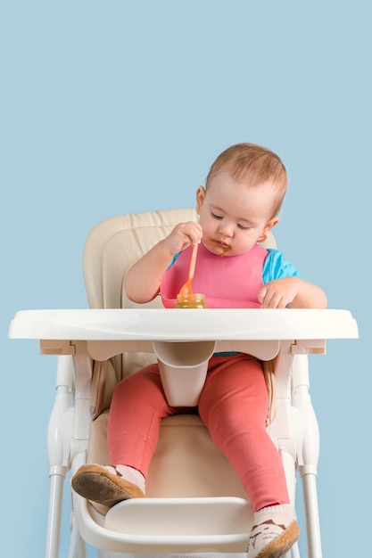 Baby isst Gemüsepüree auf einem Hochstuhl sitzend