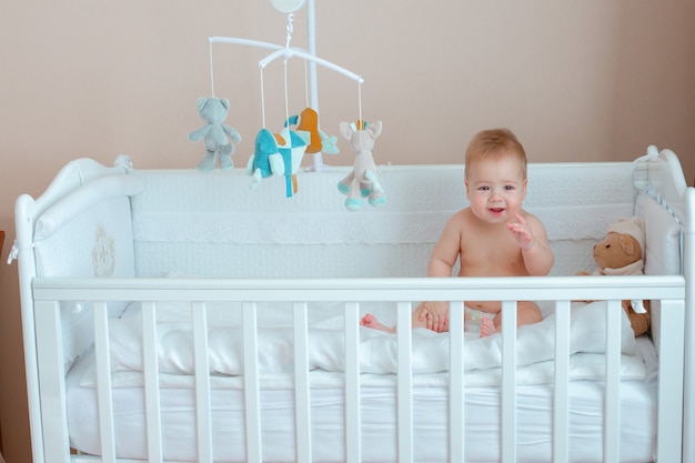 Baby Junge sitzt in einem Babybett in einer Windel