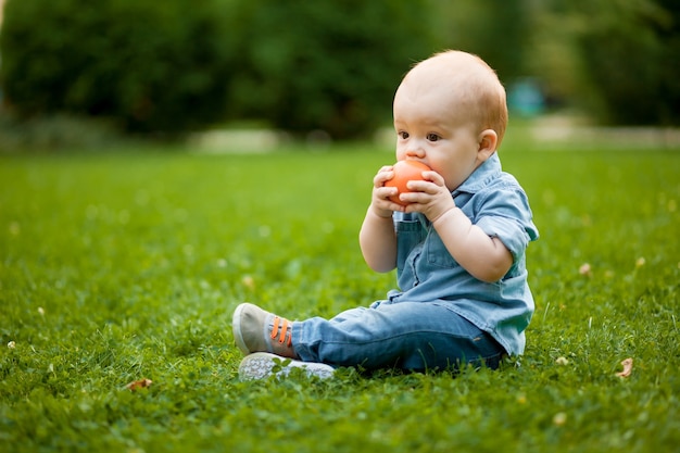 Baby kaut einen Ball auf dem Rasen im Park