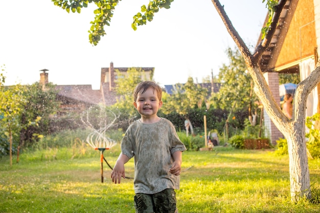 Baby Kid mientras juegan con el bastón de agua en un jardín. Concepto: Libertad, felicidad, tiempo libre.