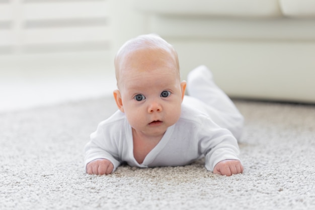 Baby, Kindheit, Menschenkonzept - Porträt eines kriechenden Babys auf dem Boden.