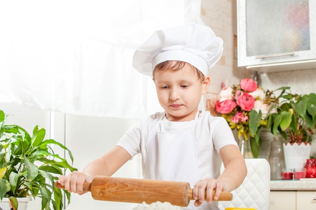 Baby kneten den Teig in Mehl