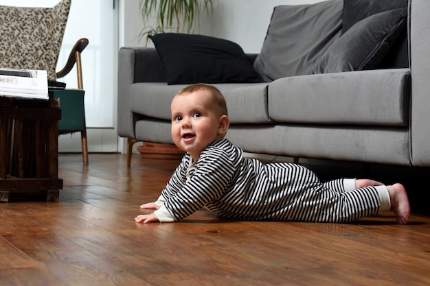 Baby krabbelt zu Hause auf dem Boden, mit Holzboden