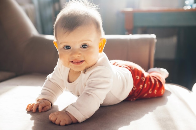 Baby liegt auf dem Bauch auf dem Bett und blickt in die Kamera und lächelt Babypflege Schönheit Gesicht Körperpflege