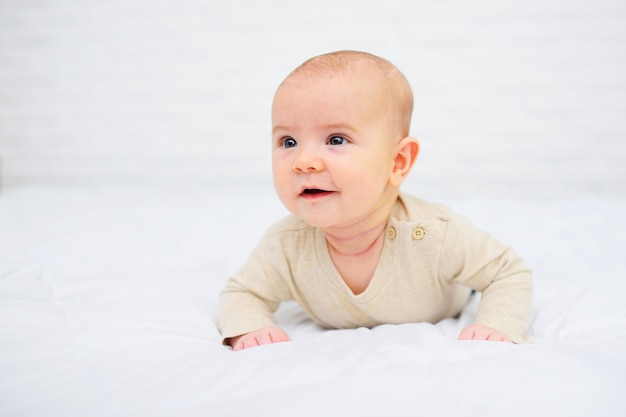 Baby liegt auf dem Bauch und lächelt auf Weiß