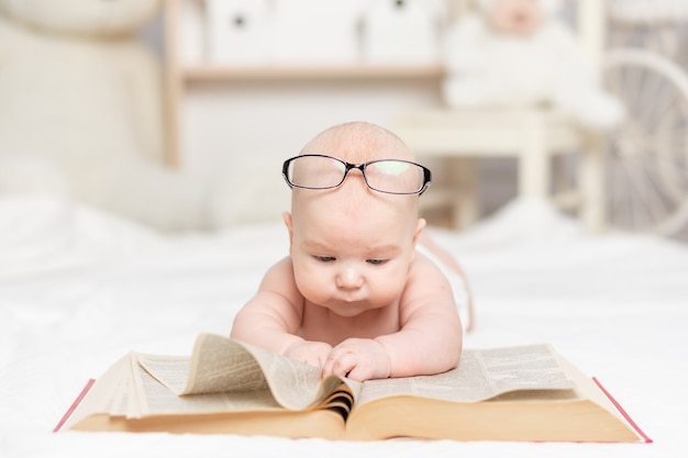 Baby liest ein Buch oder schaut es im Kinderzimmer an, Lern- und Entwicklungskonzept