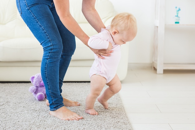 Baby macht erste Schritte mit Hilfe der Mutter zu Hause