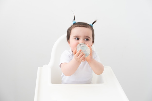 Baby Mädchen im Babystuhl Trinkwasser aus Babyflasche.