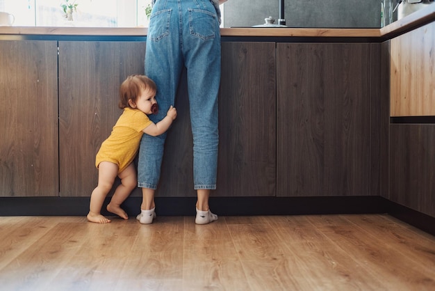 Baby Mädchen stehen Mütter Beine zu Hause in der Küche Babypflege