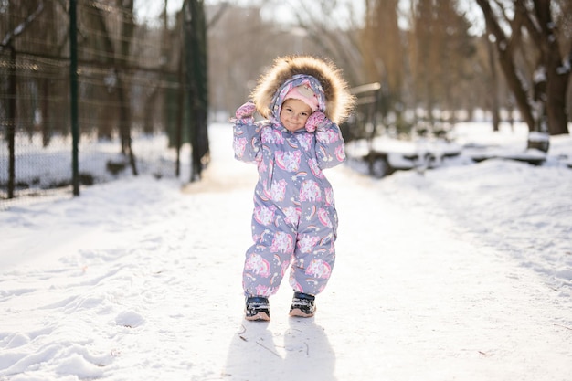 Baby Mädchen tragen Kinderschneeanzug an einem sonnigen frostigen Wintertag