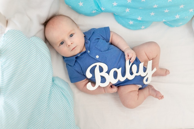 Baby mit der Aufschrift Baby in der Krippe unter den Kissen, das Konzept von Babywäsche und Textilien