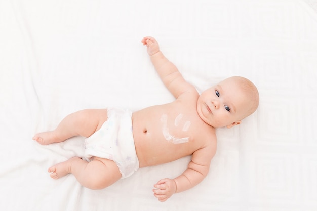 Baby mit einem Lächeln auf seinem Bauch auf einem hellen Hintergrund