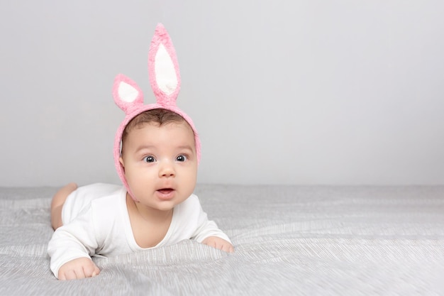 Baby mit Hasenohren liegt auf einem grauen Lichtbett Das Konzept eines Happy Easter Mockup für Werbedesign Feier Postkarten Kopierbereich