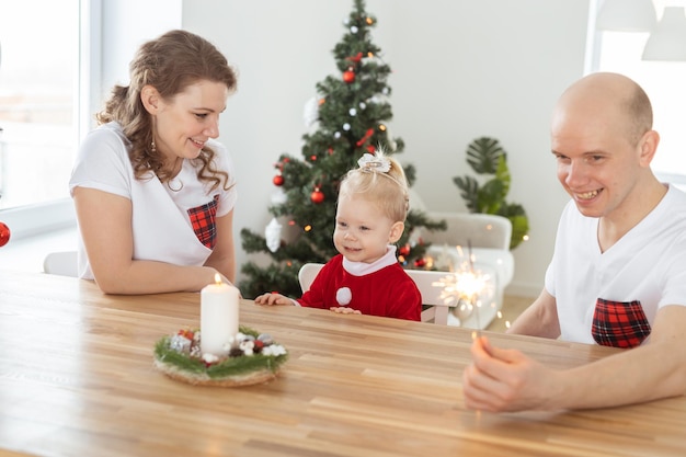 Baby mit Hörgerät und Cochlea-Implantat, das sich mit den Eltern im Weihnachtszimmer amüsiert Gehörlose Vielfalt und Gesundheit und Vielfalt