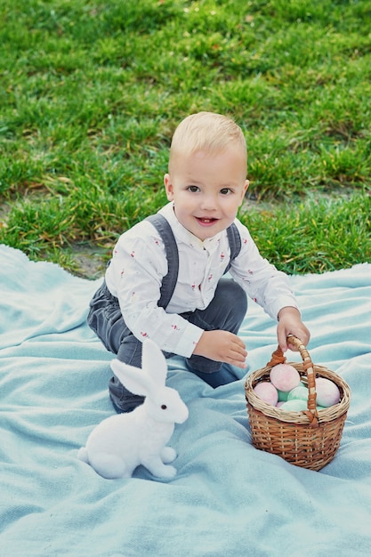 Baby mit kaninchen und eiern für ostern im park auf grünem gras