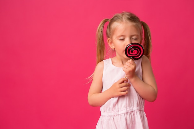 Baby mit Lutscher auf rosa Hintergrund