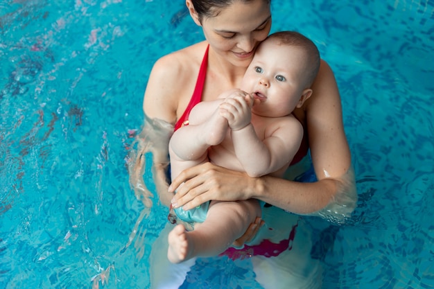 Baby mit Mutter lernt im Pool zu schwimmen