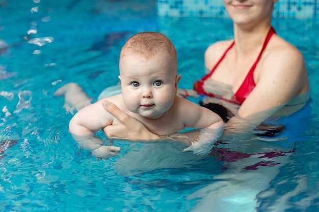 Baby mit Mutter lernt im Pool zu schwimmen