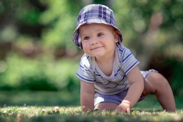 Foto baby mit netter blauer kappe, die auf dem grünen gras im garten kriecht