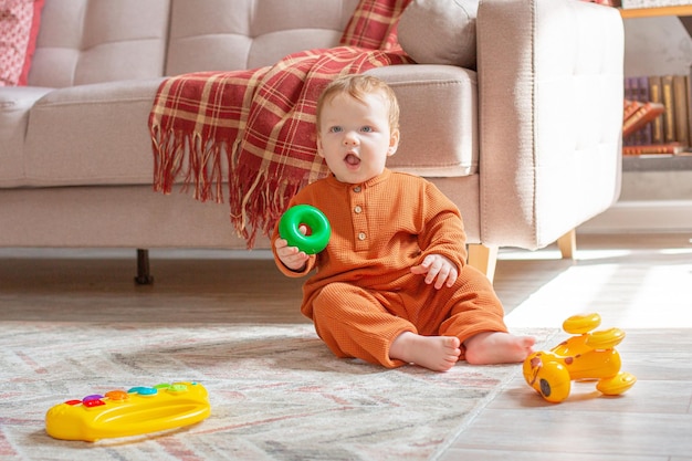 Baby mit Spielzeug krabbelt zu Hause auf dem Boden