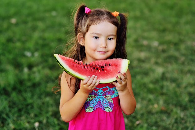 Baby-nettes asiatisches Mädchen, das saftige Wassermelone und das Lächeln isst