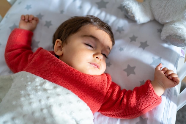 Baby Nickerchen in der Krippe Ein Jahr alter kaukasischer Junge, der sich hinlegt