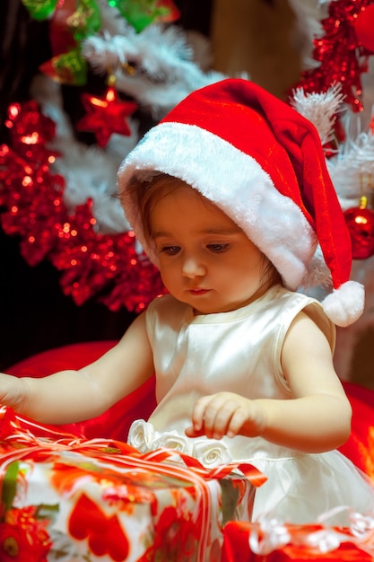 Baby öffnet ihr erstes Weihnachtsgeschenk. Neujahr. Weihnachtsstimmung.