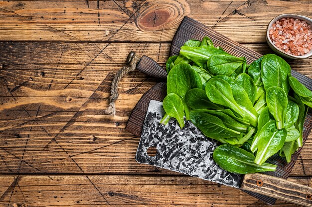 Baby romain hojas de ensalada verde sobre tabla de cortar de madera