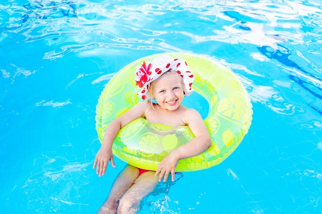 Baby schwimmt im Sommer im Pool mit einem aufblasbaren gelben Kreis, dem Konzept von Reisen und Erholung und lächelt in Panama pan