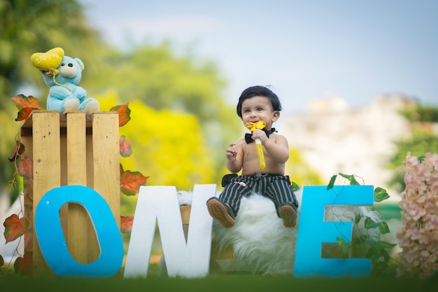 Baby sitzt auf Box und Buchstaben herum und spielt mit Spinner in der Hand in schwarzer Hose