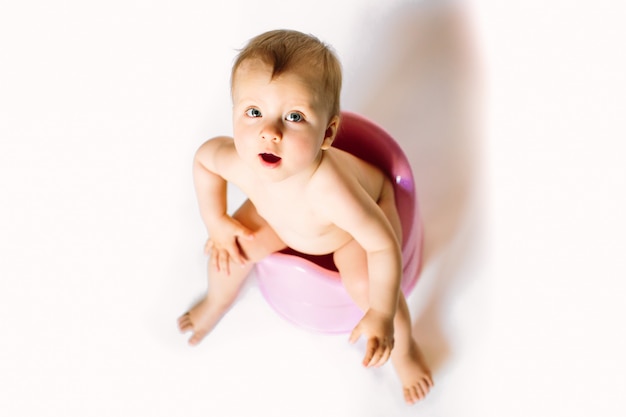 Baby sitzt auf einem Kindertopf, Toilette auf einem weißen Hintergrund