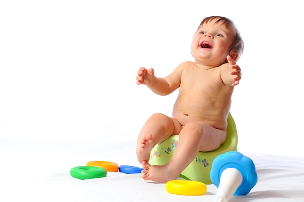 Baby sitzt auf Töpfchen und spielt Spielzeug