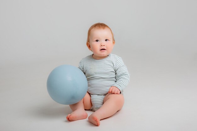 Baby sitzt mit einem blauen Ballon